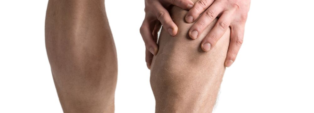 Man holds his calf muscles in pain as he deals with symptoms of peripheral artery disease