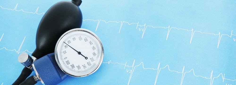 Blood pressure pump and stopwatch over an ekg reading of a heartbeat
